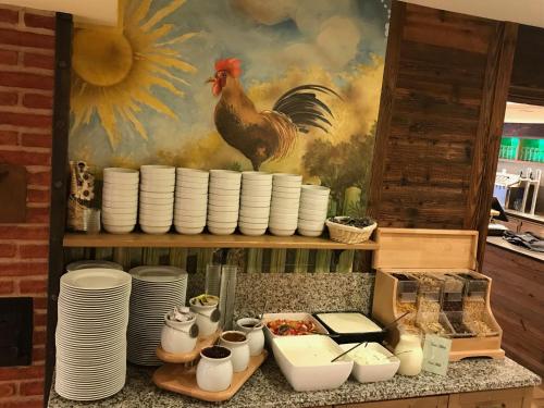 a kitchen counter with plates and a chicken on a painting at Voralpenhotel Schmoller in Sankt Georgen im Attergau