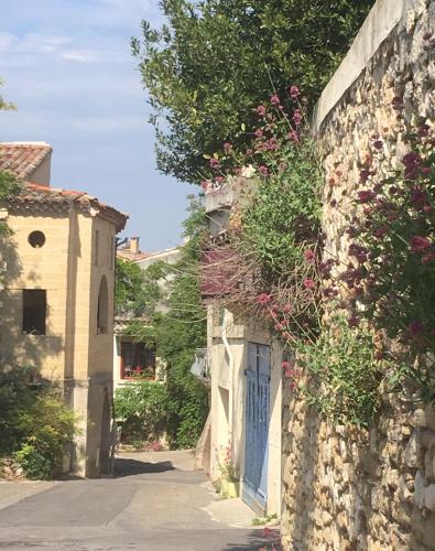 een stenen gebouw met een blauwe deur en bloemen bij Nid d'Artiste in Saint-Quentin-la-Poterie