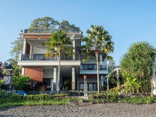 a building with palm trees in front of it at Amed Beach Villa in Amed