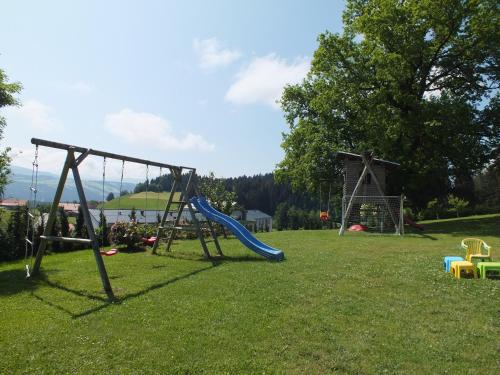 einen Spielplatz mit Rutsche im Gras in der Unterkunft Gästehaus Pension Bergwald in Scheidegg