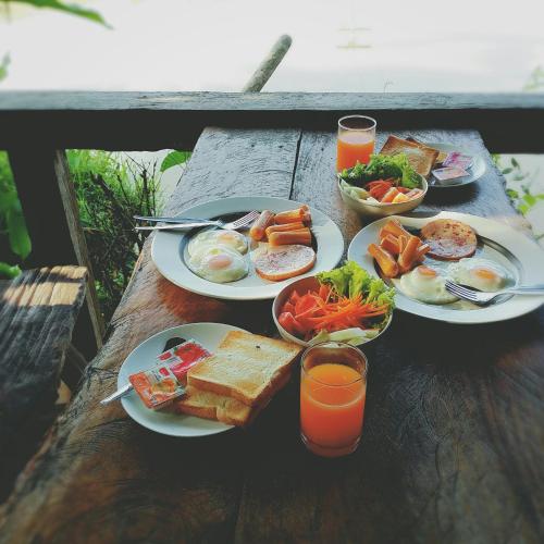 uma mesa de madeira com pratos de comidas e bebidas para o café da manhã em Suankafae Resort สวนกาแฟรีสอร์ท em Suratthani