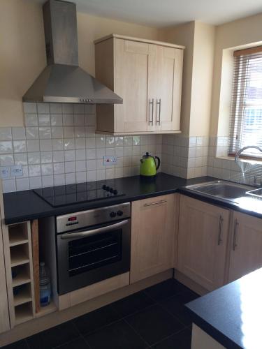 a kitchen with wooden cabinets and a stove top oven at Beautiful Kingston apartment in Kingston upon Thames