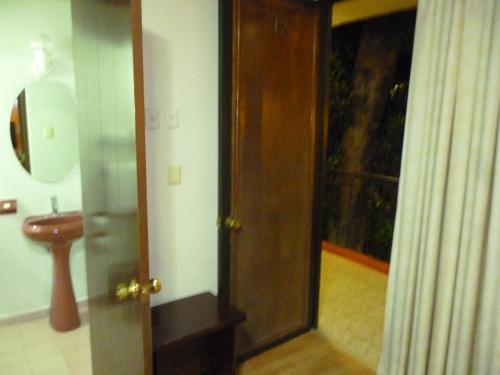 a bathroom with a sink and a door with a mirror at Hotel La Casona del Llano in Oaxaca City