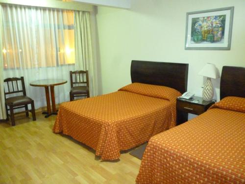 a hotel room with two beds and a table and chairs at Hotel La Casona del Llano in Oaxaca City