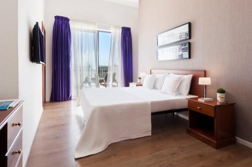 Sliema Hotel by ST Hotels في سليمة: غرفة نوم بسرير كبير مع ستائر ارجوانية