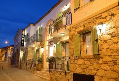 a building with green shutters on a street at night at Brothers Cesme Hotel in Cesme