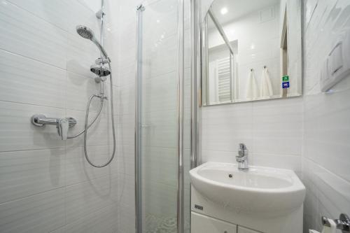 a white bathroom with a shower and a sink at White Vision Apartment in Opole