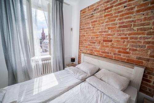 een slaapkamer met een bakstenen muur en een bed met kussens bij White Vision Apartment in Opole