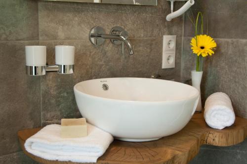 a bathroom with a white bowl sink and towels at Hotel Am Moosrain Garni in Eitting