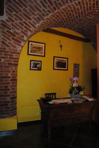 a room with a yellow wall and a wooden table at All'Ombra del Castello in Cigliè