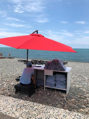 a man sitting at a desk under an umbrella on the beach at Dreamland oasis in Chakvi in Chakvi