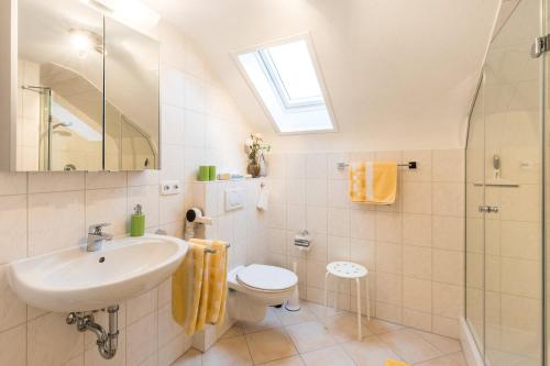 ein Bad mit einem Waschbecken, einem WC und einem Fenster in der Unterkunft Ferienwohnung Hortensie in Markdorf