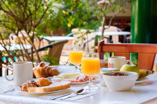 a table with breakfast foods and glasses of orange juice at Hostal ROM Familiar in Roses