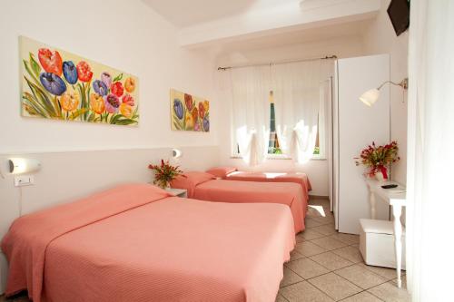 two beds in a hotel room with pink sheets at Hotel Lydia in Alassio