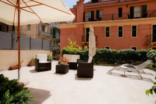a patio with chairs and an umbrella and a table and chairs at Hotel Lydia in Alassio