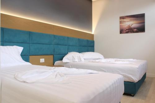 two beds in a hotel room with white sheets at Domus Hotel & Apartments in Shëngjin