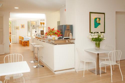 a kitchen with white counters and white tables and chairs at Hotel Lydia in Alassio
