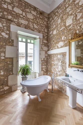 a bathroom with a large tub and two sinks at La Maison in Siracusa