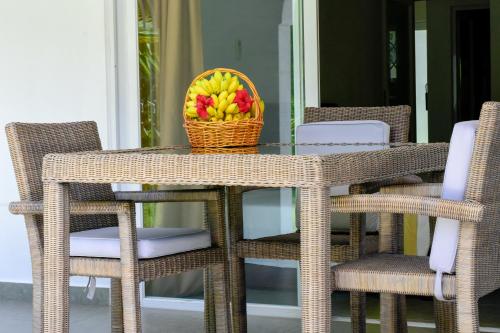 a wicker table and chairs with a basket of fruit at HideAway in Anse Possession