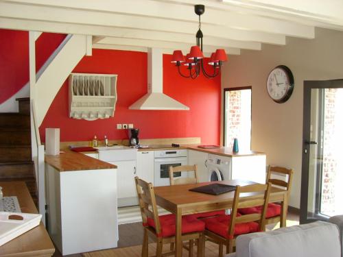 een keuken met rode muren en een tafel en stoelen bij Gite Le Bois Roger in Widehem