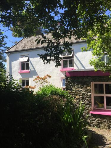 ein weißes Haus mit rosa Fenstern und Bäumen in der Unterkunft Boss’s farmhouse in Valentia Island