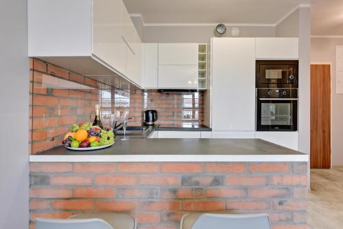 a kitchen with a bowl of fruit on a counter at GRANO APARTMENTS Gdańsk Motława SPA & Wellness in Gdańsk