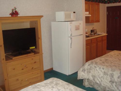 a kitchen with a white refrigerator and a tv at Townhouse Inn & Suites Omaha in Omaha