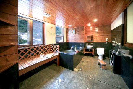a bathroom with a tub and a sink and a toilet at Ming Lu Holiday Hotel in Renai