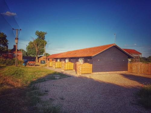 a building with a fence next to a house at Plumptons Farm Holiday Lodges in Colchester