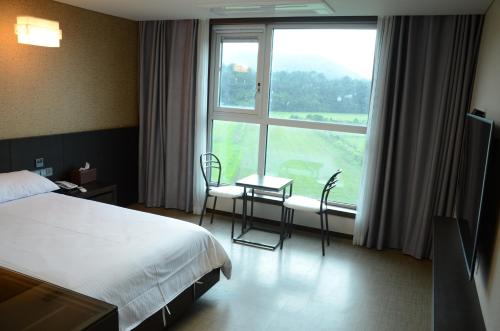 a hotel room with a bed and a large window at Jeju Stay in Sungsan in Seogwipo