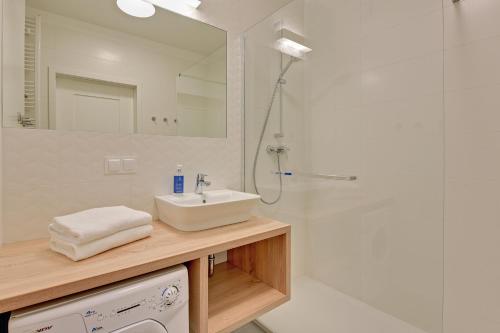a white bathroom with a sink and a shower at GRANO APARTMENTS Gdańsk Motława SPA & Wellness in Gdańsk