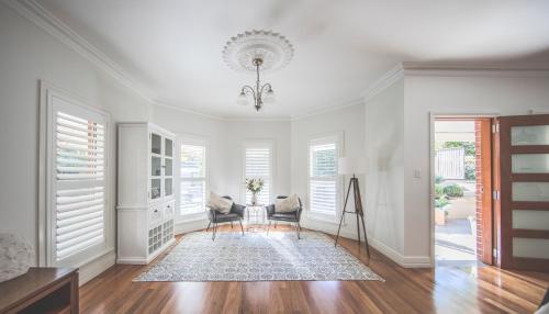 a living room with white walls and a chandelier at Diggers Beach Cottage in Coffs Harbour