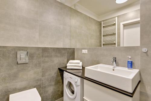 a bathroom with a washing machine and a sink at GRANO APARTMENTS Gdańsk Motława SPA & Wellness in Gdańsk
