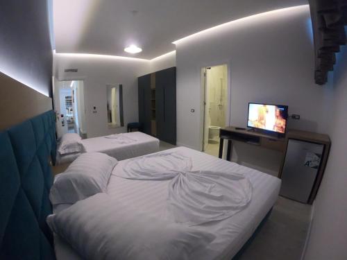 a hotel room with two beds and a television at Domus Hotel & Apartments in Shëngjin