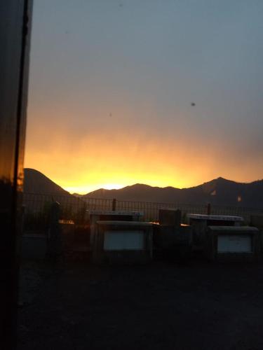 a sunset over a fence with mountains in the background at Cemara Indah Hotel in Bromo