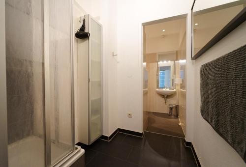 y baño con ducha acristalada y lavamanos. en Planet Berlin City Apartments, en Berlín