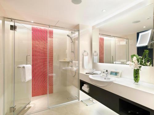 a bathroom with a shower, sink, and mirror at Sama Sama Hotel KLIA in Sepang