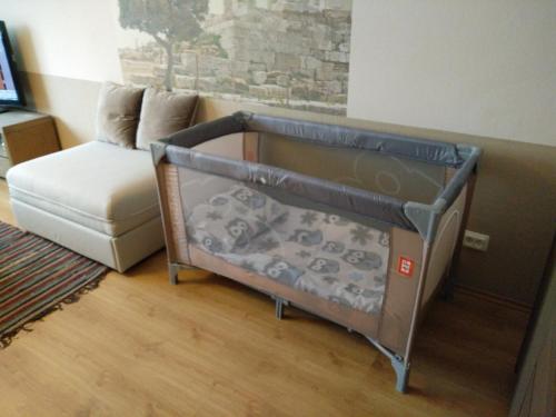 a baby crib in a room with a couch at Kaktuss Apartamenti in Valmiera