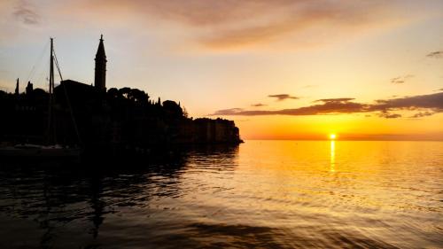 a sunset over the water with a clock tower at Charmy Rovinj in Rovinj
