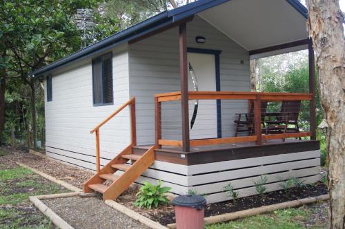 a tiny house with a porch and a deck at Sapphire Beach Holiday Park in Coffs Harbour
