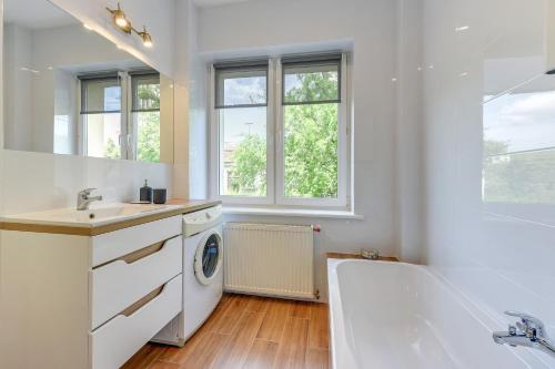 La salle de bains est pourvue d'un lavabo et d'un lave-linge. dans l'établissement Gdynia Comfort Apartments Perkuna, à Gdynia