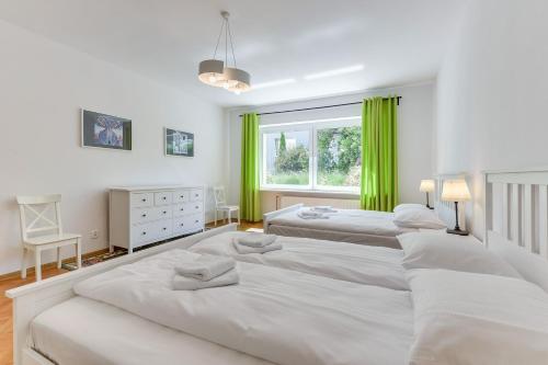 グディニャにあるGdynia Comfort Apartments Perkunaの緑のカーテンが備わるベッドルームのベッド2台