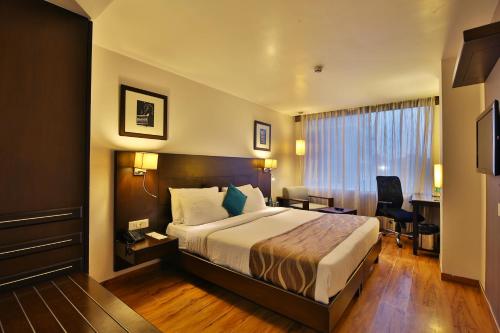 a hotel room with a bed and a desk at Hotel Clarks Collection Vadodara in Vadodara