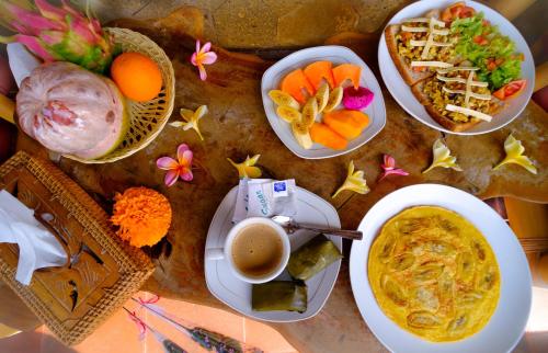 einen Tisch mit Teller mit Essen und eine Schüssel Suppe in der Unterkunft Bali Ubud Harmony in Ubud