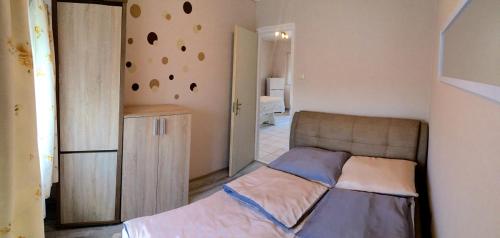 a small bedroom with a bed and a wall with a wall with holes at Nika nyaraló jakuzzival in Balatonkeresztúr