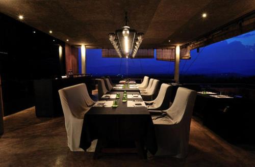 a dining room with a long table and white chairs at Sala Khaoyai in Wangkata