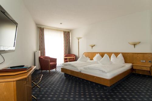 a hotel room with a bed and a flat screen tv at Weinhotel Rose in Volkach