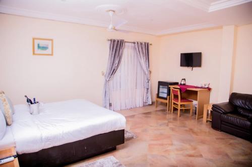 a bedroom with a bed and a desk and a couch at Eden Vale Hotel in Ajiringano