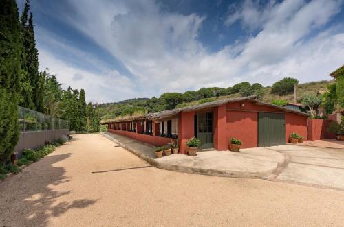 a red building with potted plants in front of it at Can Mora de Dalt in Sant Vicenç de Montalt