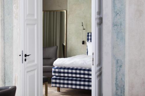 a bedroom with a bed and a chair in a room at Hotel Pacai, Vilnius, a Member of Design Hotels in Vilnius